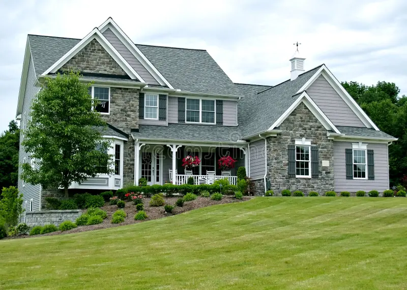 Two-story suburban home with stone and siding exterior, landscaped lawn, and multiple windows representing Siding Contractors, general contractor, window replacement, builders near me, and bath remodel company services.