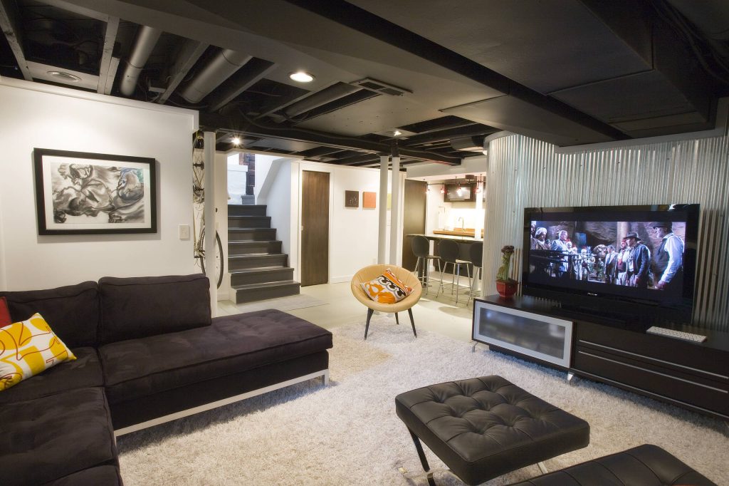 Finished modern basement created by Basement remodelers, featuring a comfortable entertainment area, sectional seating, television, bar, contemporary lighting, and design inspiration from basement renovation companies, basement finishing companies, basement finishing contractors, and basement remodeling ideas.