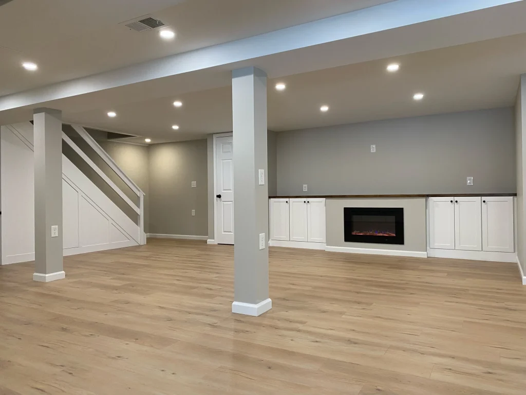 Modern finished basement by basement remodelers near me, featuring wood-look flooring, recessed lighting, built-in cabinets, fireplace, and an open living area designed by a basement remodeler, basement remodeling contractor near me, basement finishing, and basement renovation contractor.