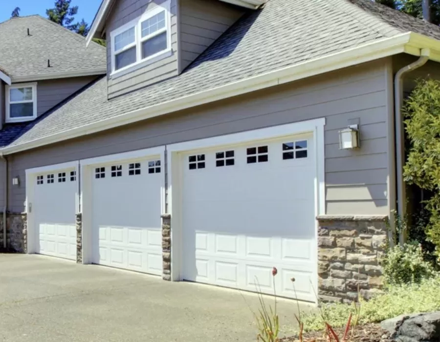 Garage door replacement near me featuring three white residential doors with decorative windows for homeowners planning garage door replacement, comparing garage door replacement cost, selecting a replacement garage door, or looking to replace garage door systems.