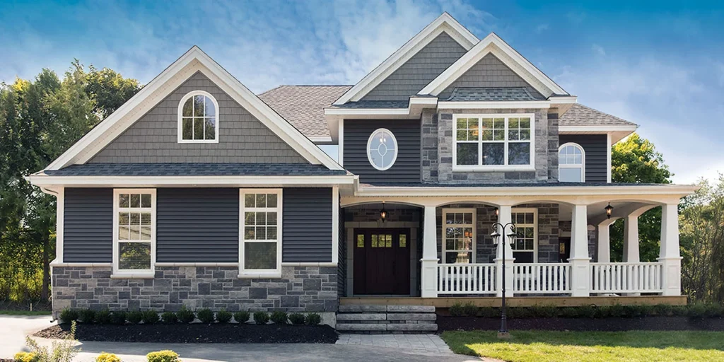 Hamilton Vinyl Siding on a beautiful two-story home with dark blue siding, stone accents, and white trim, showcasing design options for homeowners researching a siding installer in Hamilton, vinyl siding in Hamilton, a siding contractor in Hamilton, and siding replacement in Hamilton.