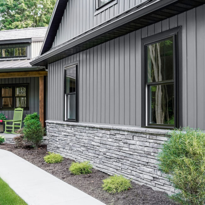 Modern home exterior featuring dark vertical siding and stone accents representing Home exterior contractors, local siding companies, siding installation companies, exterior remodeling contractors, and a new siding contractor.