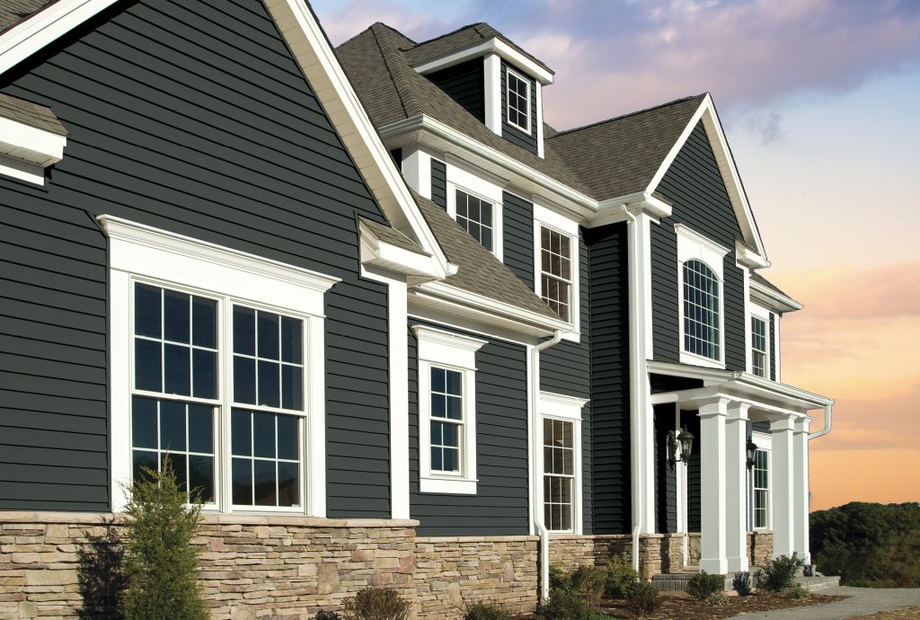 Beautiful home exterior with dark siding, white trim, large windows, and stone accents representing Home exterior contractors, local siding companies, siding installation companies, exterior remodeling contractors, and a new siding contractor.